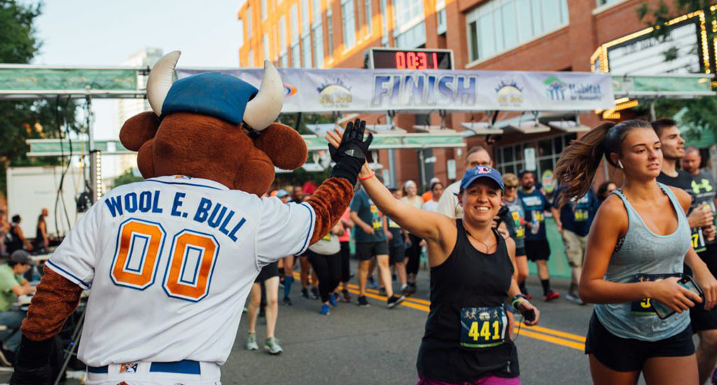 Photo of Wool E. Bull high-fiving runner in Bull Moon 5K